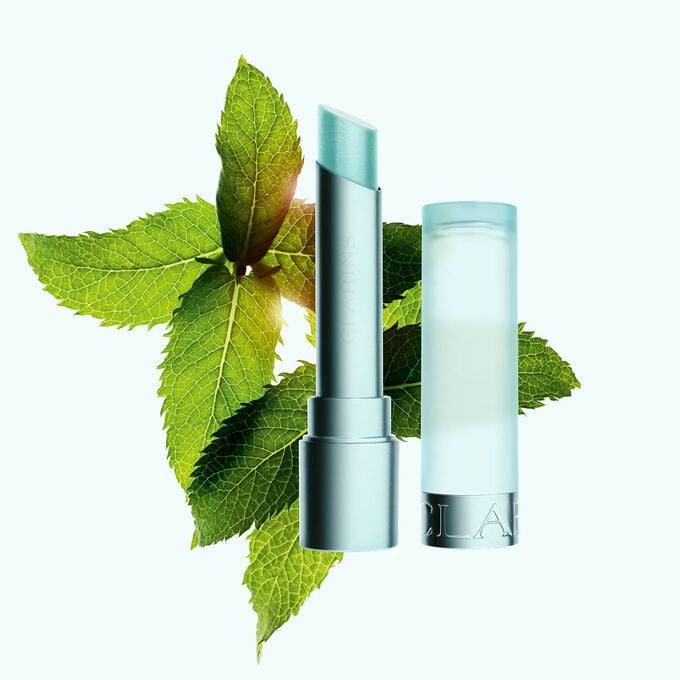 Imagem do b&aacute;lsamo labial refrescante da Clarins, real&ccedil;ado pela presen&ccedil;a de hortel&atilde; ao redor, destacando a sua sensa&ccedil;&atilde;o refrescante.