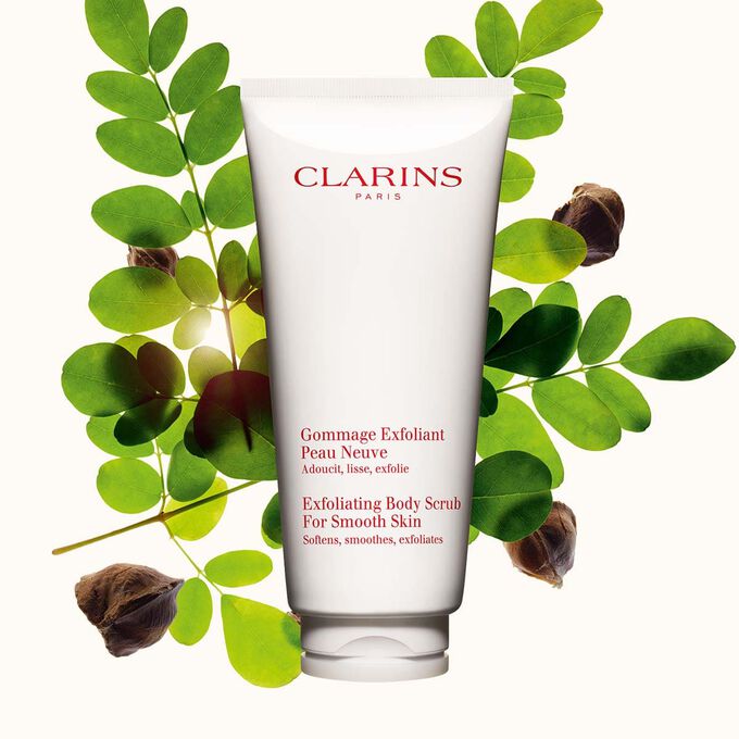 Imagem da embalagem do Clarins Gommage Exfoliant Peau Neuve ao lado de nozes de moringa sobre um fundo bege claro