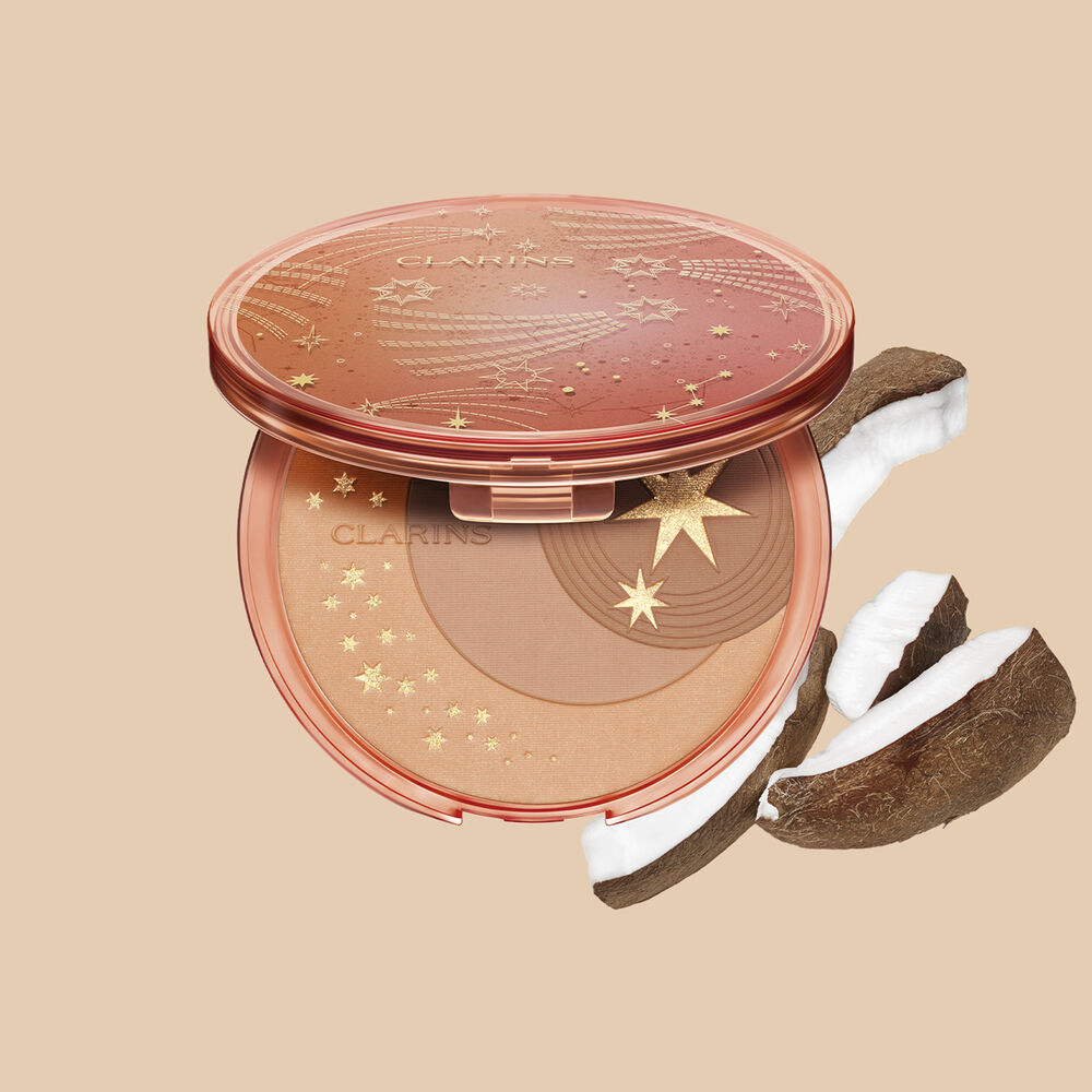 Imagem do produto pó compacto bronzeador da Clarins, apresentado ao lado de fatias de coco sobre um fundo branco