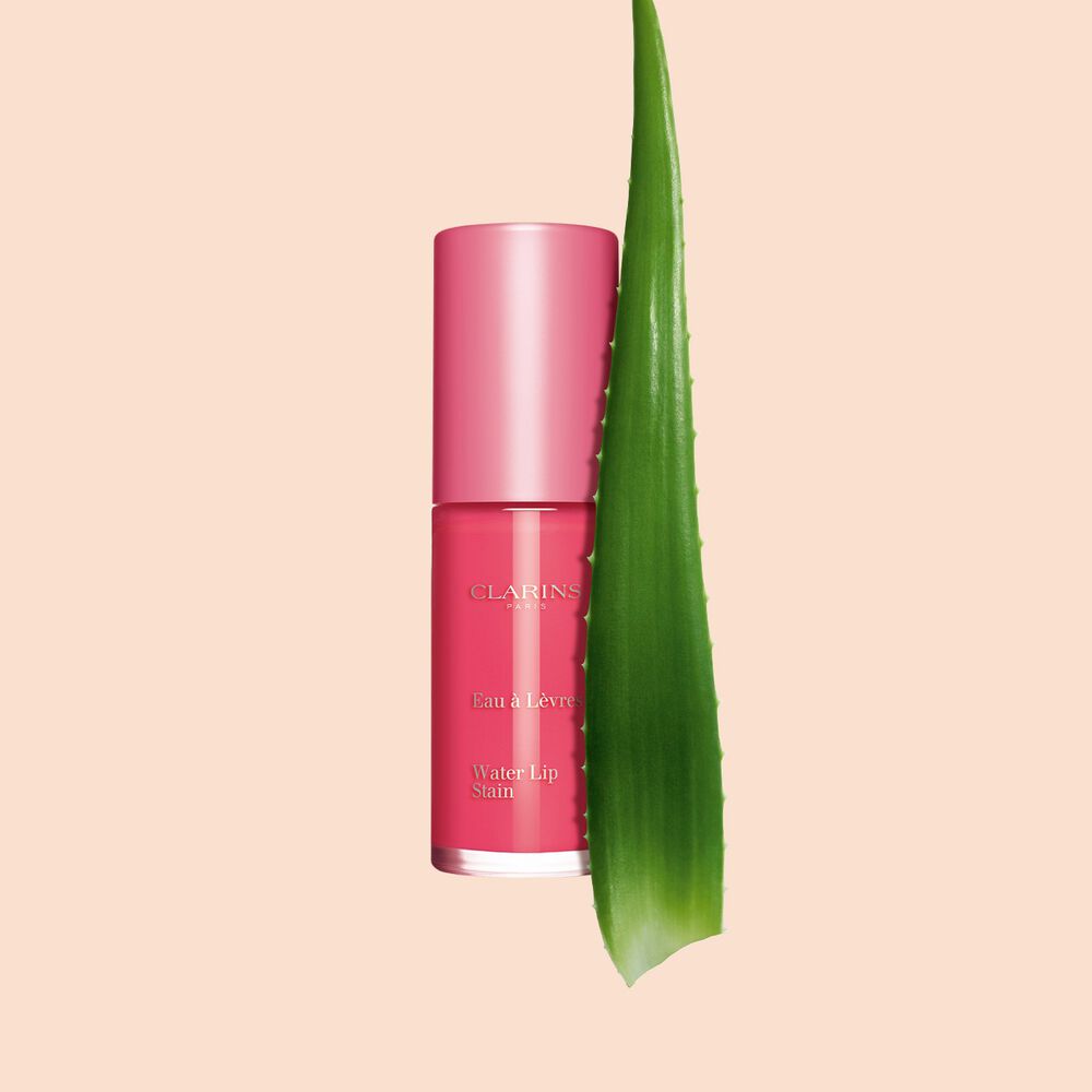 Imagem do produto novo batom cor-de-rosa da Clarins junto a uma planta de aloé vera sobre um fundo branco