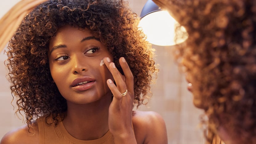 Uma mulher que se olha ao espelho, à procura do creme antirrugas certo para as necessidades da pele". Uma mulher que se olha ao espelho, à procura do creme antirrugas certo para as necessidades da pele".